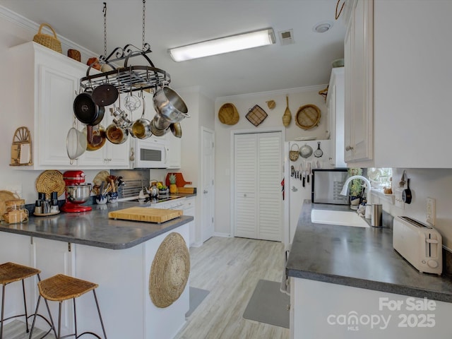 433 Linsbury Ct, Gastonia, NC 28056 - kitchen with crown molding, dark countertops, a sink, a peninsula, and white microwave