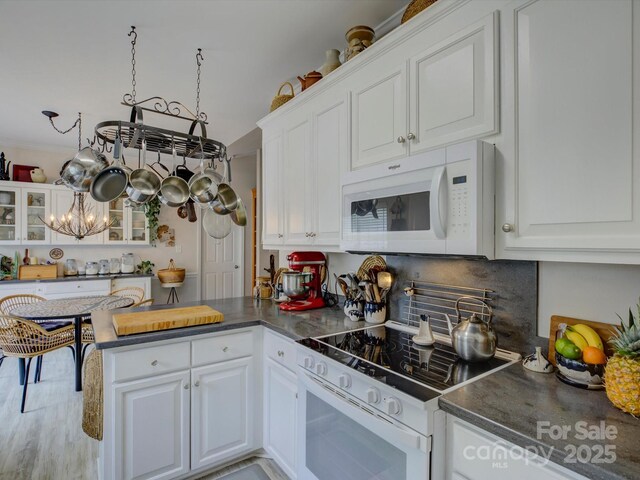 433 Linsbury Ct, Gastonia, NC 28056 - kitchen with white cabinets, dark countertops, white appliances, a peninsula, and glass insert cabinets
