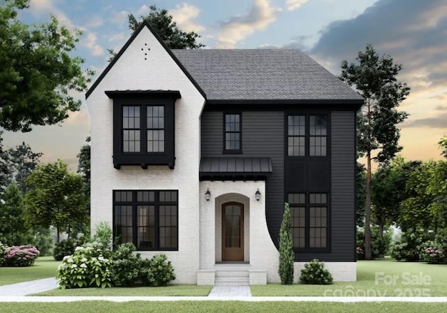french provincial home featuring a lawn, brick siding, and roof with shingles