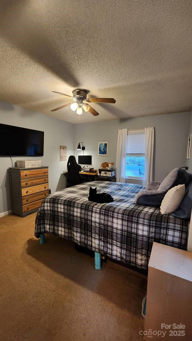 bedroom with carpet, a ceiling fan, and a textured ceiling