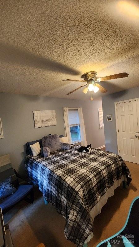 bedroom featuring carpet floors, ceiling fan, and a textured ceiling