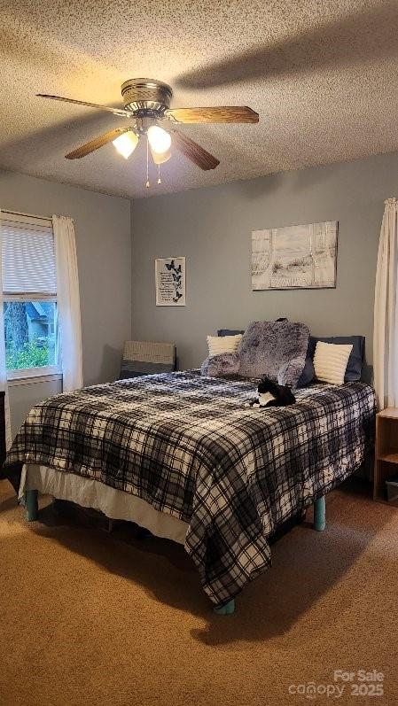 bedroom featuring carpet flooring, a textured ceiling, and ceiling fan