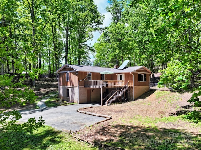 rear view of property featuring a chimney, driveway, and stairway