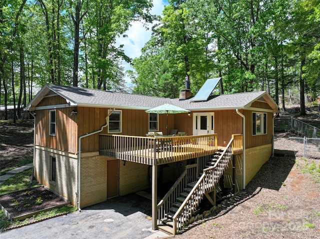 rear view of property featuring stairs, fence, brick siding, a chimney, and a shingled roof
