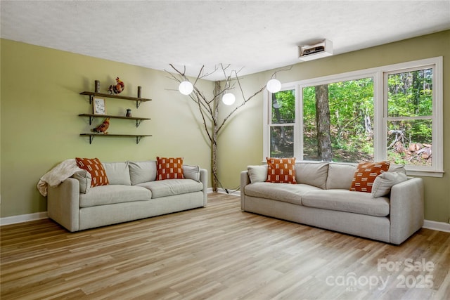 living room featuring wood finished floors, baseboards, and a textured ceiling