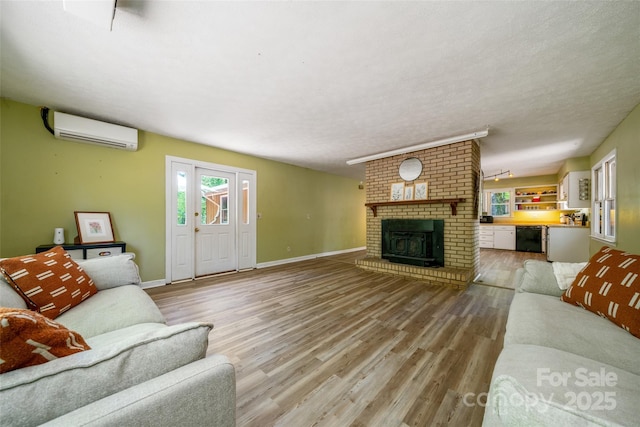 living room featuring a wall mounted air conditioner, wood finished floors, a fireplace, baseboards, and a textured ceiling