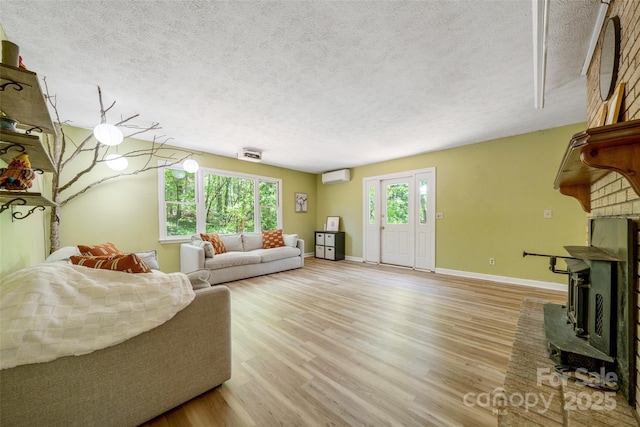 living area featuring a textured ceiling, light wood-style floors, baseboards, a wall mounted air conditioner, and a fireplace
