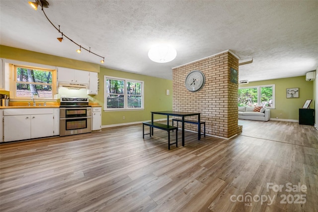 dining room with light wood finished floors, baseboards, a textured ceiling, and an AC wall unit