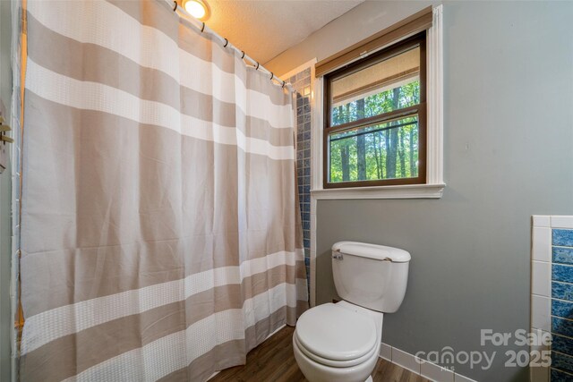 full bathroom featuring wood finished floors, toilet, curtained shower, and baseboards