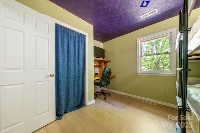 office space with wood finished floors, built in desk, and baseboards