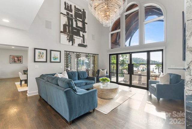 living area with an inviting chandelier, baseboards, a high ceiling, and dark wood-style flooring