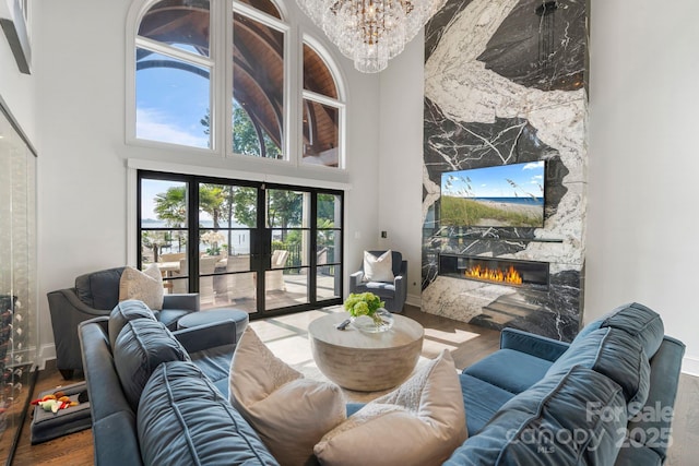 living area with a towering ceiling, wood finished floors, and a premium fireplace