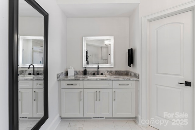 bathroom with a sink, visible vents, two vanities, and marble finish floor