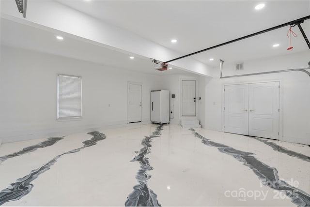 garage featuring recessed lighting, a garage door opener, and visible vents