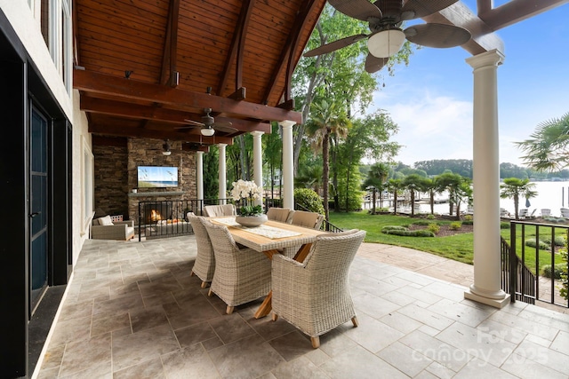 view of patio featuring outdoor dining space, ceiling fan, and an outdoor stone fireplace