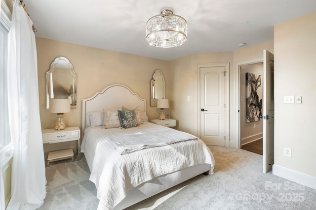 carpeted bedroom featuring baseboards and a notable chandelier