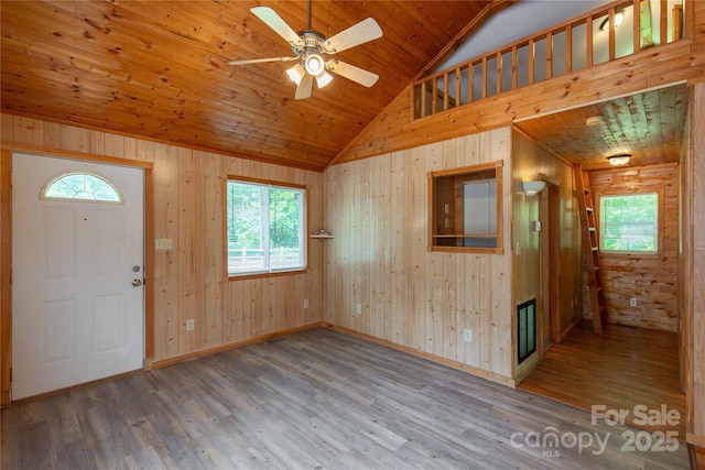 foyer entrance with healthy amount of natural light, wood finished floors, lofted ceiling, wood walls, and wood ceiling