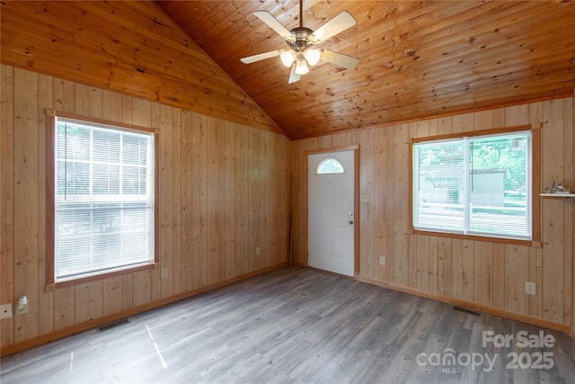 empty room featuring vaulted ceiling, a ceiling fan, wood finished floors, wood walls, and wood ceiling