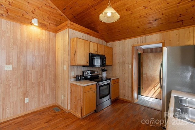 kitchen with stainless steel appliances, vaulted ceiling, dark wood-style floors, light countertops, and wood walls