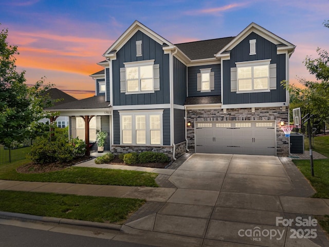 view of front of house featuring a garage, board and batten siding, concrete driveway, and stone siding