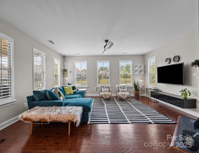 living room with baseboards, visible vents, and wood finished floors