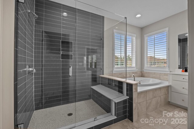 bathroom featuring tile patterned flooring, a bath, and a shower stall