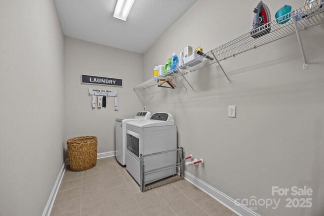 laundry area with light tile patterned floors, baseboards, laundry area, and washing machine and dryer
