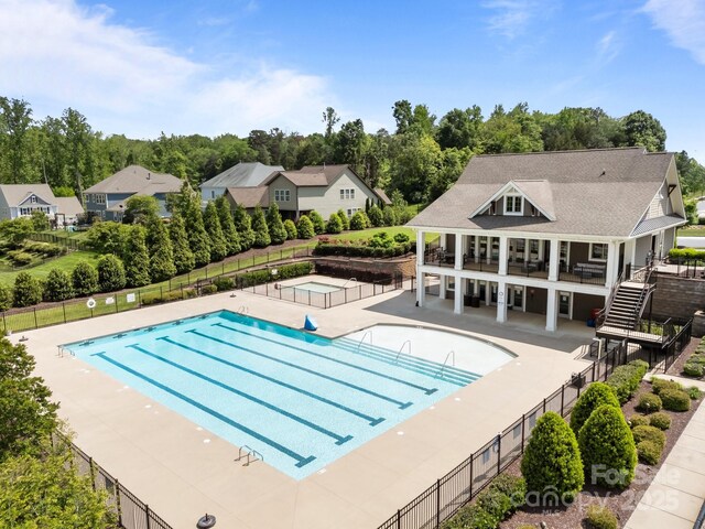 community pool featuring a hot tub, a patio, and fence