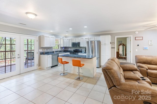 kitchen with crown molding, a kitchen breakfast bar, open floor plan, and appliances with stainless steel finishes