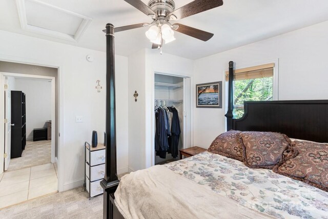 bedroom with a closet, attic access, light colored carpet, a ceiling fan, and light tile patterned floors