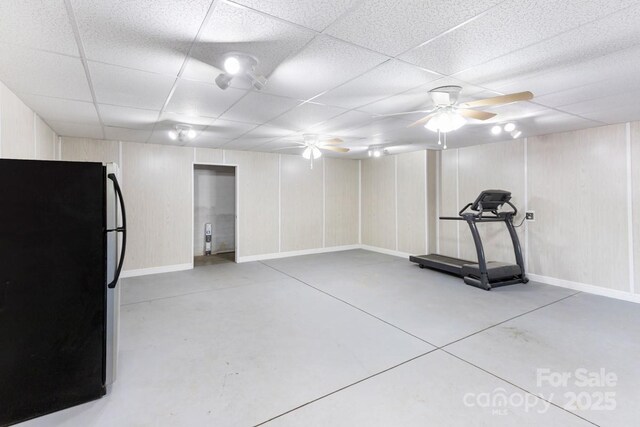 below grade area with freestanding refrigerator, a ceiling fan, baseboards, and a paneled ceiling