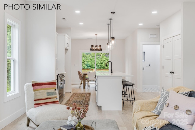 living room with baseboards, recessed lighting, light wood-style flooring, and visible vents