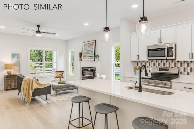 kitchen featuring stainless steel appliances, open floor plan, light wood-type flooring, and a sink