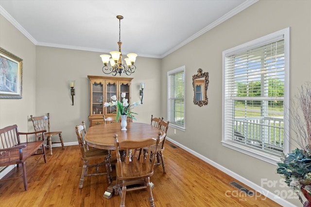 dining space with an inviting chandelier, baseboards, light wood-type flooring, visible vents, and ornamental molding