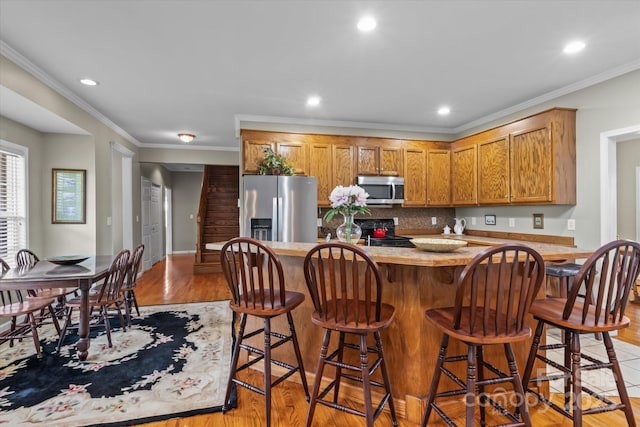 kitchen featuring appliances with stainless steel finishes, light wood-style floors, light countertops, recessed lighting, and tasteful backsplash