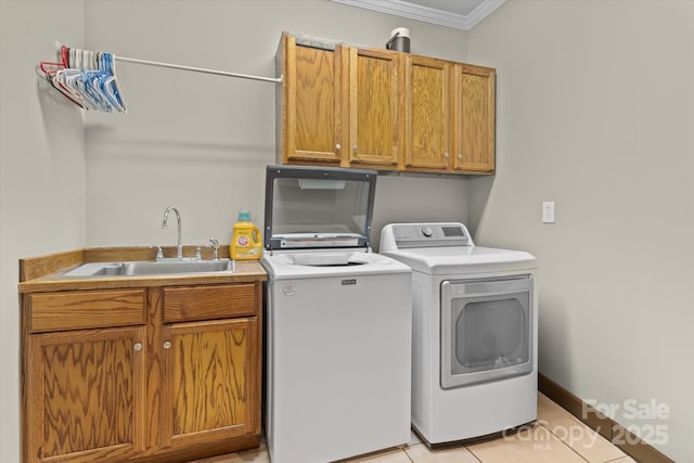 laundry area featuring cabinet space, crown molding, washing machine and clothes dryer, a sink, and light tile patterned floors