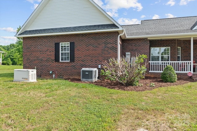 view of side of home with brick siding, a shingled roof, a yard, and cooling unit