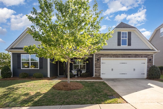 view of front of house featuring an attached garage, stone siding, concrete driveway, and a front yard