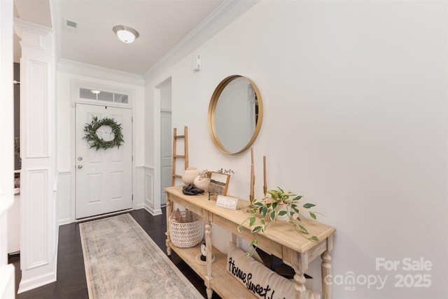 foyer with ornate columns, dark wood-style floors, ornamental molding, and visible vents