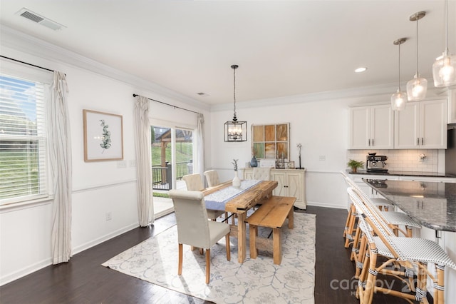 dining area featuring visible vents, ornamental molding, baseboards, dark wood-type flooring, and a chandelier
