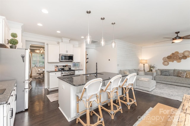 kitchen featuring dark wood-style flooring, a sink, an island with sink, stainless steel appliances, and a ceiling fan