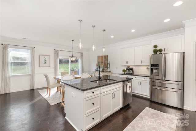 kitchen with appliances with stainless steel finishes, a sink, a center island with sink, dark stone countertops, and dark wood-style floors