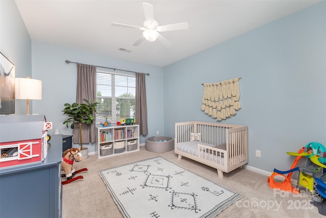 carpeted bedroom featuring visible vents, a crib, and baseboards