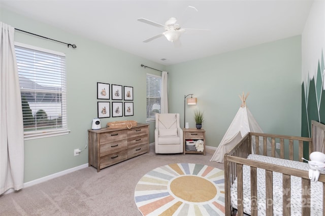 bedroom featuring baseboards, carpet, ceiling fan, and a crib