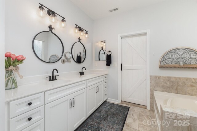 full bath with double vanity, a sink, a bath, and visible vents