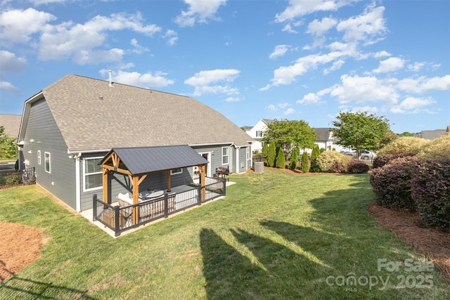 rear view of house with a yard and roof with shingles