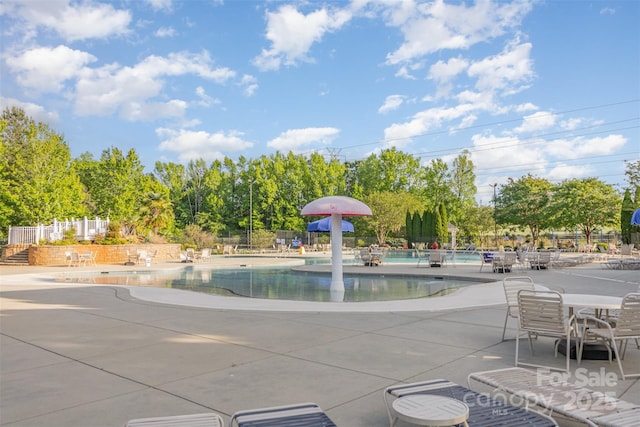 community pool with fence and a patio area
