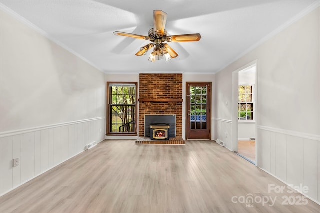 unfurnished living room with crown molding, a ceiling fan, wood finished floors, and visible vents