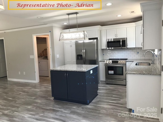kitchen with a kitchen island, washer / clothes dryer, a sink, ornamental molding, and stainless steel appliances