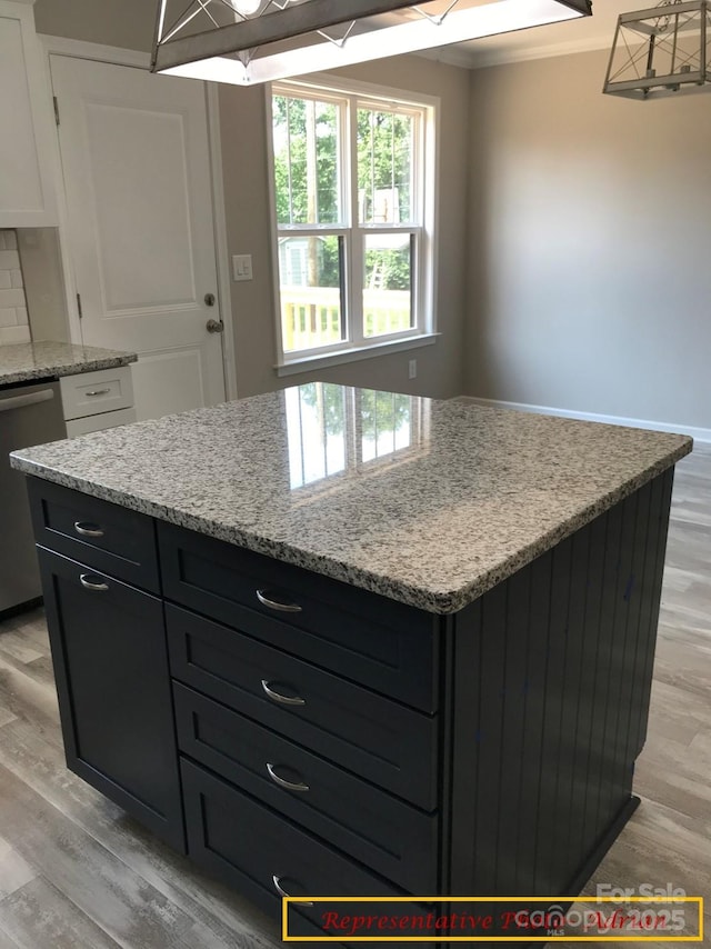 kitchen with light stone counters, dark cabinetry, light wood-style flooring, and dishwasher